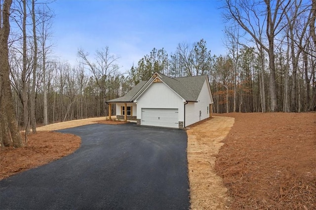 view of property exterior featuring aphalt driveway, an attached garage, and roof with shingles