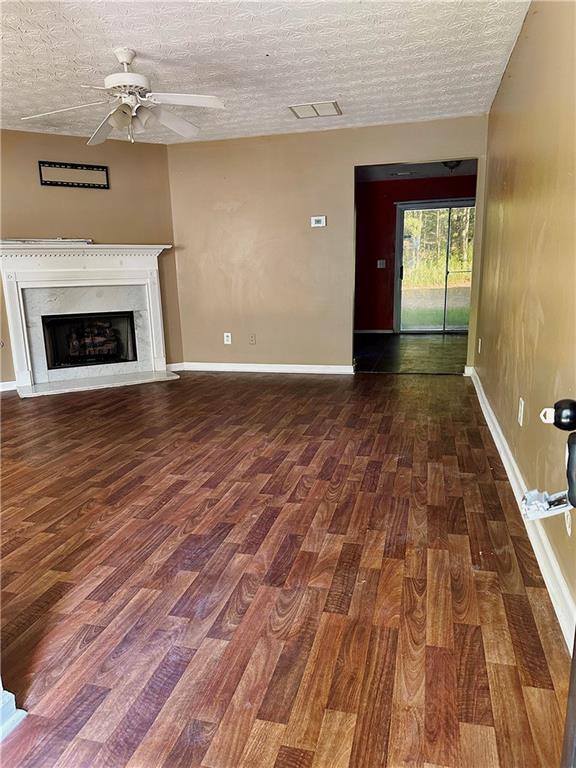 unfurnished living room with dark hardwood / wood-style flooring, a textured ceiling, and ceiling fan