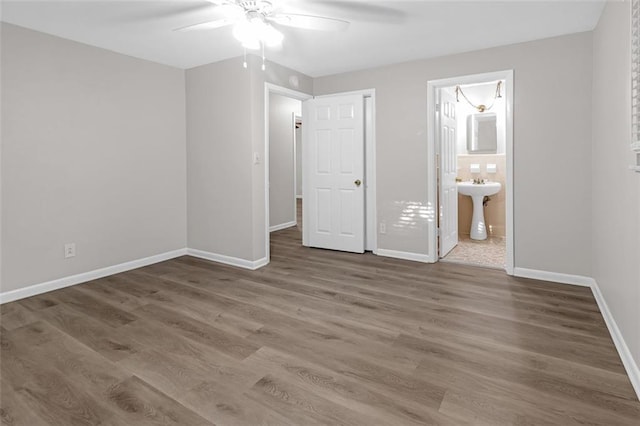 unfurnished bedroom featuring ceiling fan, hardwood / wood-style floors, connected bathroom, and sink