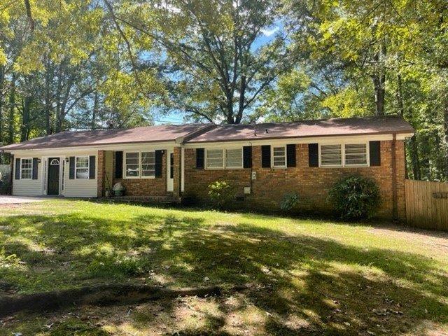 single story home featuring a front yard, brick siding, and fence