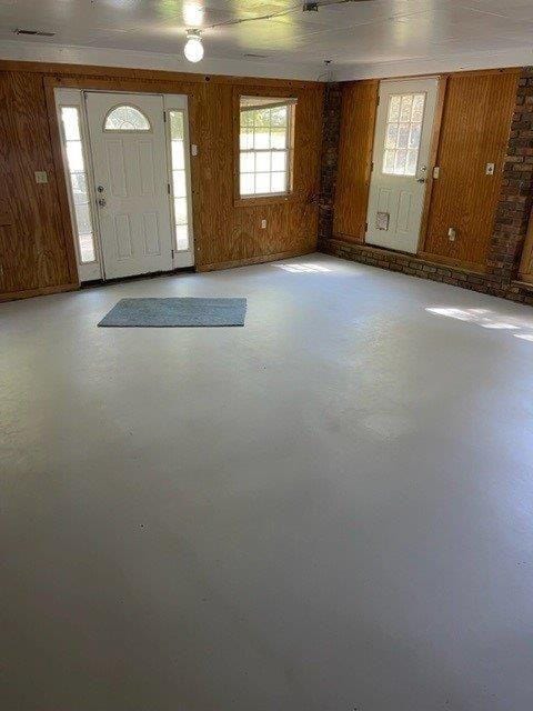 foyer with concrete flooring and wooden walls