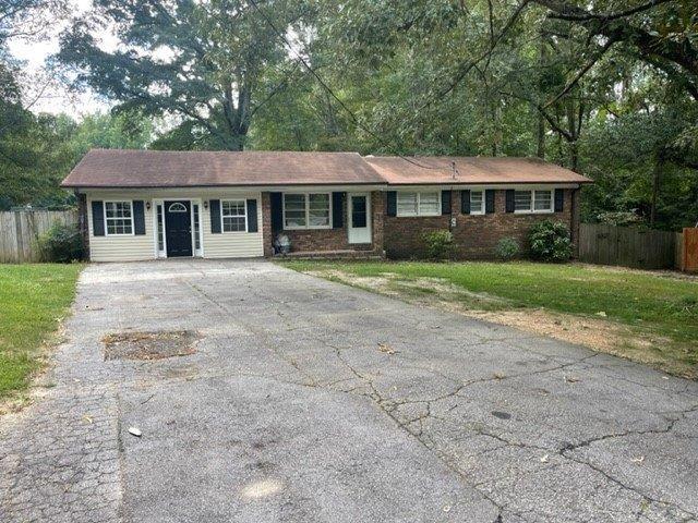 ranch-style house with driveway, fence, and a front lawn