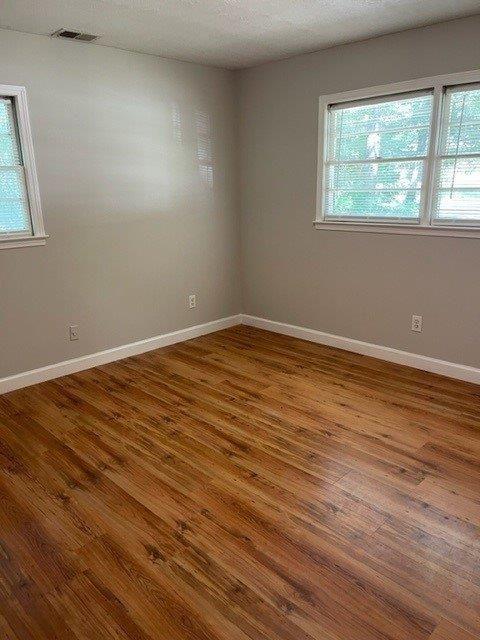 unfurnished room with hardwood / wood-style floors, a textured ceiling, and a healthy amount of sunlight