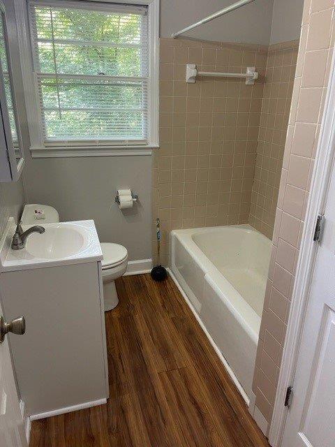 full bath with baseboards, toilet, vanity, wood finished floors, and shower / bathtub combination