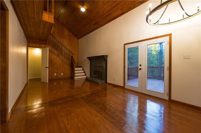 unfurnished living room featuring wood ceiling, hardwood / wood-style floors, high vaulted ceiling, a stone fireplace, and french doors