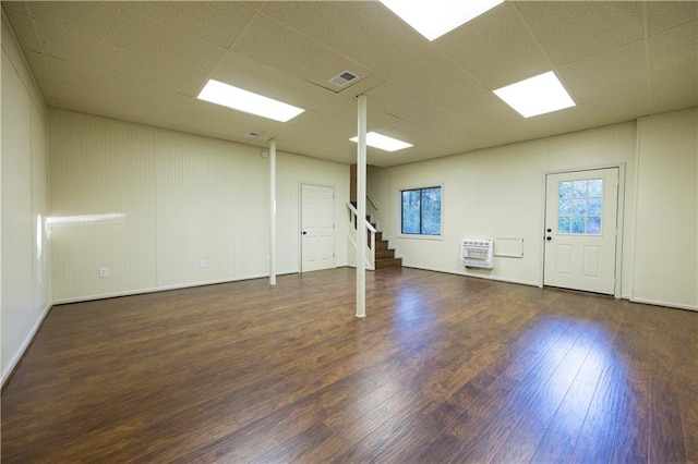 empty room featuring dark wood-type flooring, a paneled ceiling, heating unit, and plenty of natural light