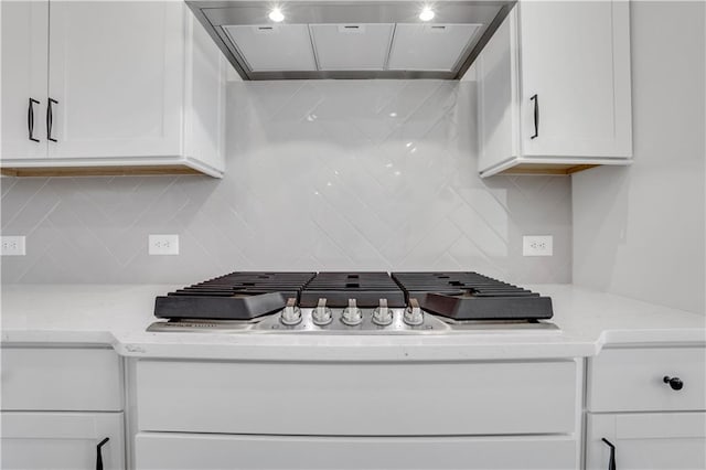 kitchen featuring stainless steel gas cooktop, white cabinetry, light stone counters, and exhaust hood