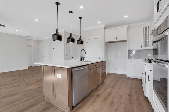 kitchen featuring white cabinets, an island with sink, stainless steel appliances, light countertops, and a sink