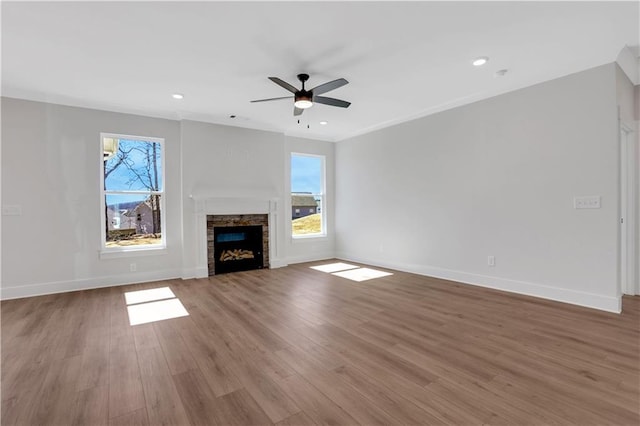 unfurnished living room with a fireplace, plenty of natural light, baseboards, and wood finished floors