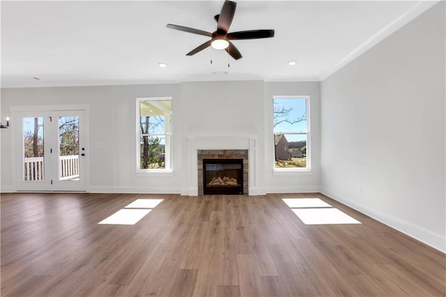 unfurnished living room featuring a wealth of natural light, baseboards, and wood finished floors