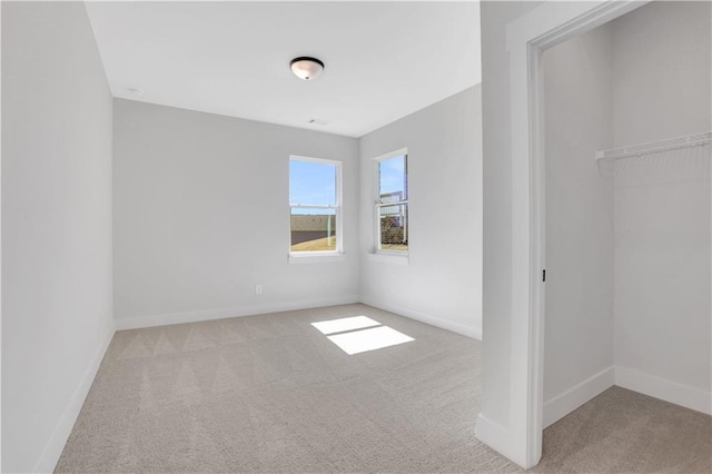 unfurnished bedroom featuring light carpet, a closet, and baseboards