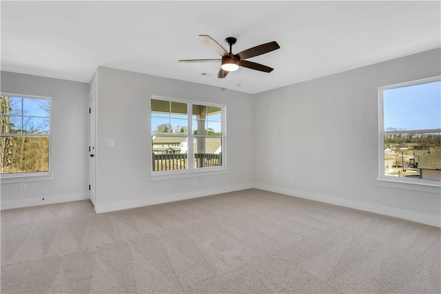 empty room featuring a wealth of natural light, light colored carpet, and baseboards