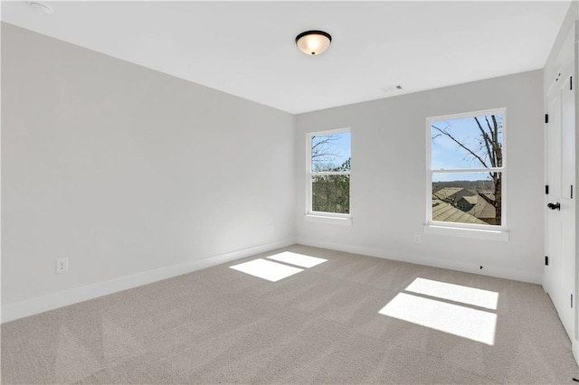 empty room featuring light carpet, visible vents, and baseboards