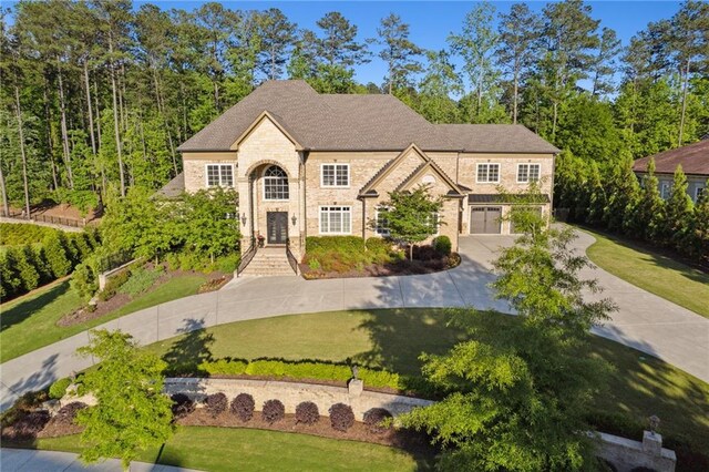 view of front of house with a front lawn, driveway, an attached garage, and stone siding