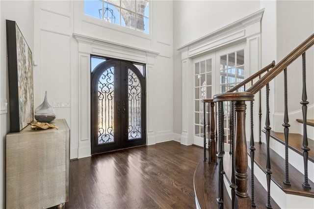 entryway featuring plenty of natural light, french doors, a towering ceiling, and wood finished floors
