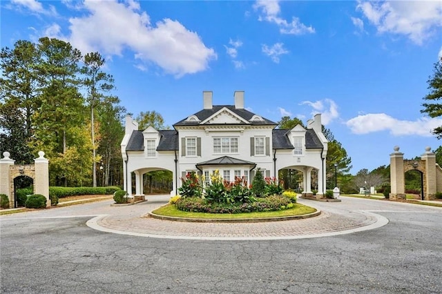 view of front facade featuring a standing seam roof, a chimney, and driveway