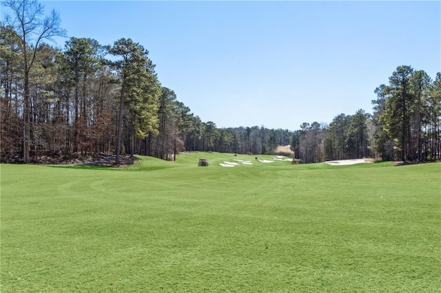 view of home's community with a lawn, a view of trees, and golf course view
