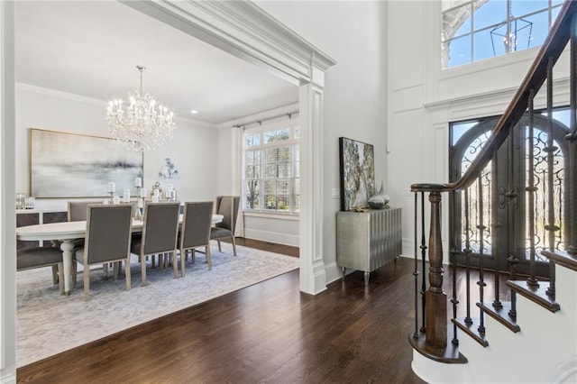entrance foyer with stairs, wood finished floors, ornamental molding, an inviting chandelier, and baseboards