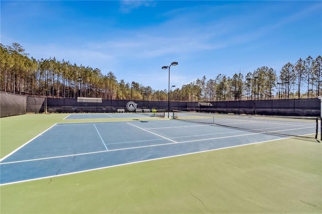 view of tennis court featuring fence and community basketball court