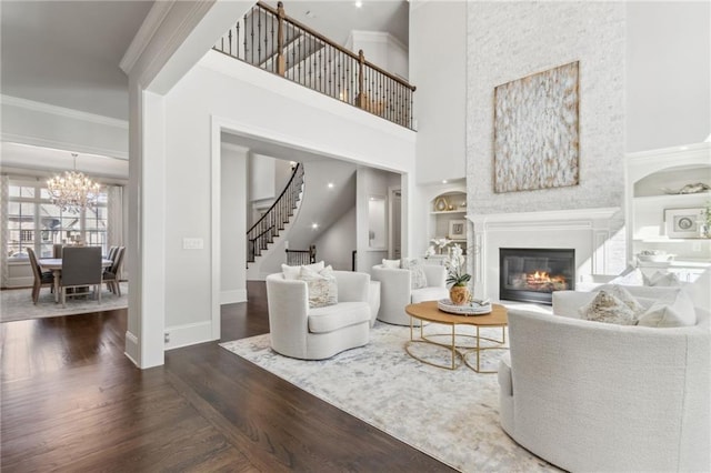 living area featuring stairs, wood finished floors, built in features, baseboards, and a glass covered fireplace