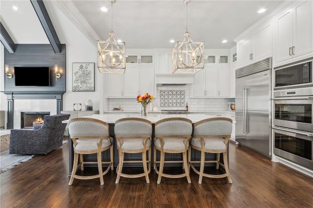 kitchen with built in appliances, a chandelier, decorative backsplash, and glass insert cabinets