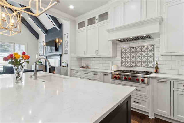 kitchen featuring stainless steel gas stovetop, an inviting chandelier, a sink, custom range hood, and white cabinets