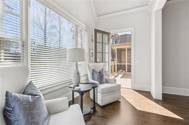 sitting room with crown molding, lofted ceiling, baseboards, and wood finished floors