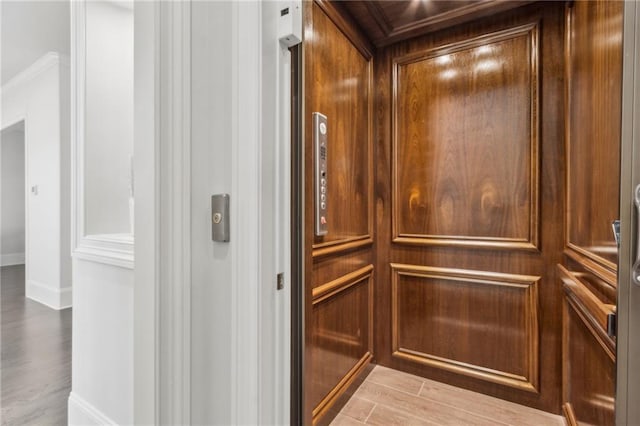 interior details featuring baseboards, elevator, and wood finished floors