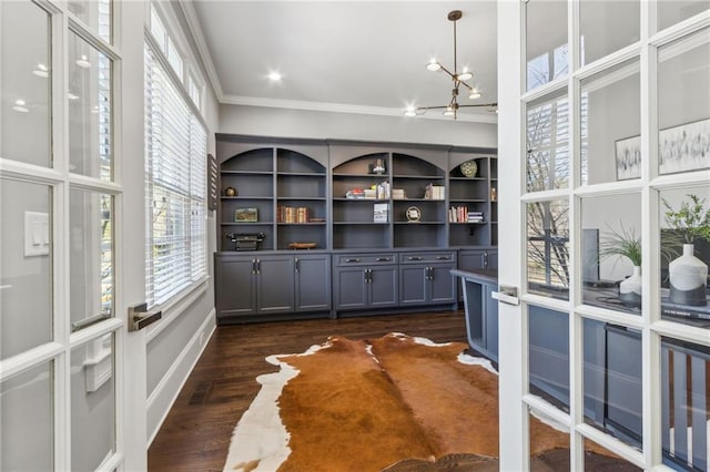interior space with an inviting chandelier, ornamental molding, and dark wood-style flooring