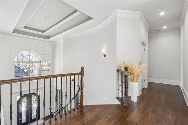 hall featuring an inviting chandelier, wood finished floors, an upstairs landing, visible vents, and baseboards