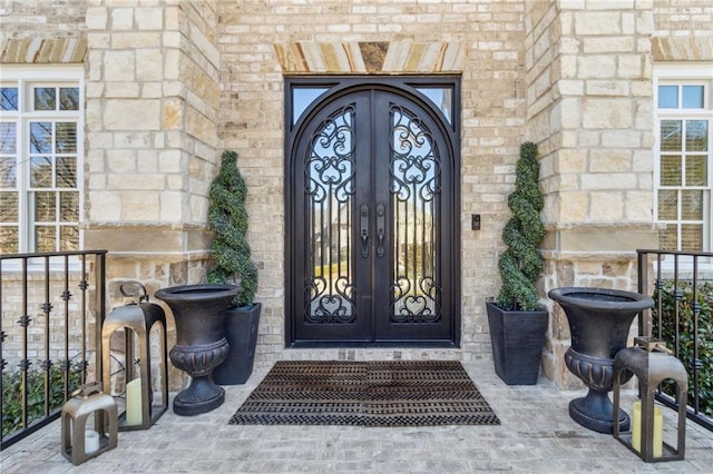 doorway to property featuring stone siding, brick siding, and french doors