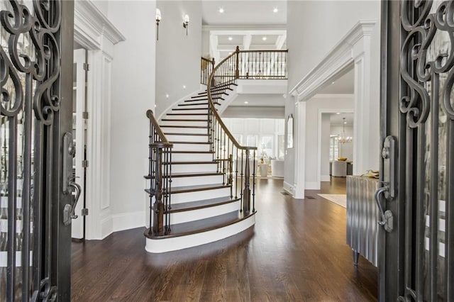 entryway featuring baseboards, stairway, dark wood finished floors, and a towering ceiling