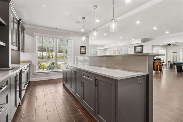 kitchen featuring pendant lighting, wood tiled floor, crown molding, a large island, and light countertops