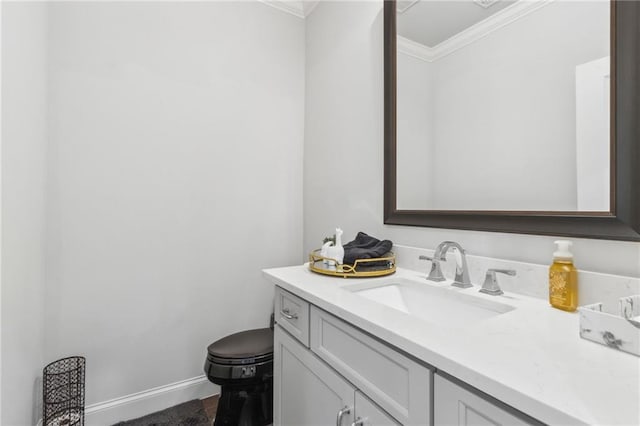 half bath featuring baseboards, ornamental molding, vanity, and toilet