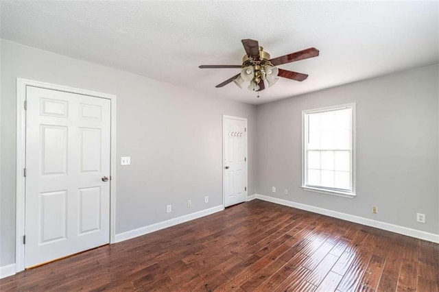 empty room with dark wood-type flooring, a textured ceiling, and ceiling fan