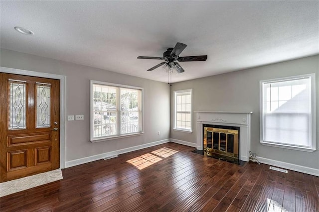 unfurnished living room with ceiling fan, a textured ceiling, and dark hardwood / wood-style flooring