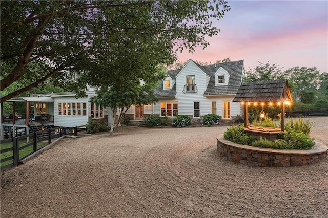 view of front of house with gravel driveway and fence