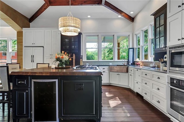 kitchen with white cabinets, beverage cooler, built in appliances, and butcher block countertops