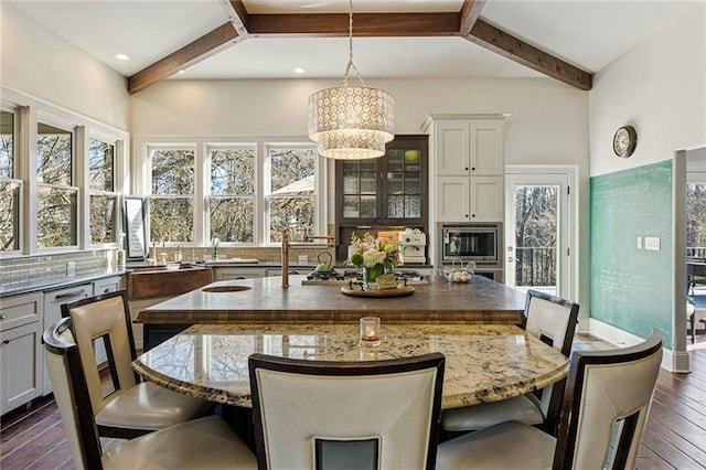 dining space with dark wood finished floors, beam ceiling, recessed lighting, and a chandelier