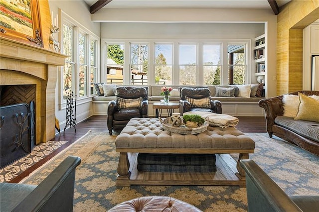 living area featuring beamed ceiling, wood finished floors, baseboards, and a high end fireplace