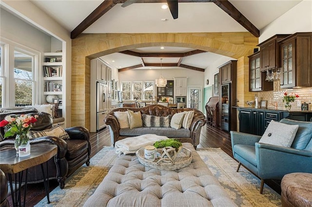 living room with vaulted ceiling with beams, light wood-style floors, arched walkways, and indoor bar