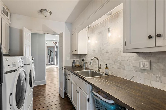 kitchen with a sink, tasteful backsplash, dark countertops, dark wood-style floors, and separate washer and dryer