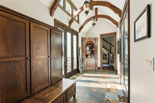 foyer with vaulted ceiling with beams, stairs, stone tile floors, french doors, and an inviting chandelier