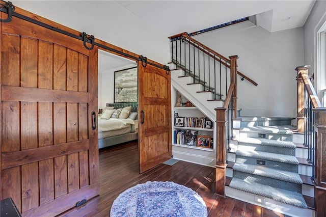 staircase with a barn door and hardwood / wood-style flooring