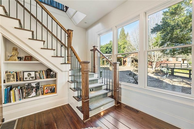 stairs with visible vents, baseboards, and wood-type flooring