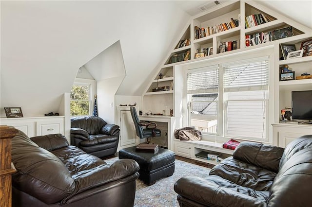 living room with visible vents, built in shelves, and wood finished floors