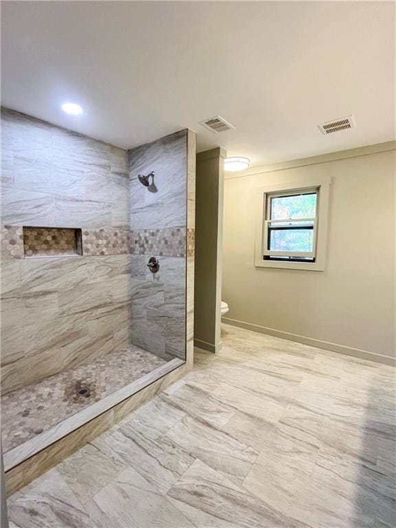 bathroom featuring a tile shower and toilet