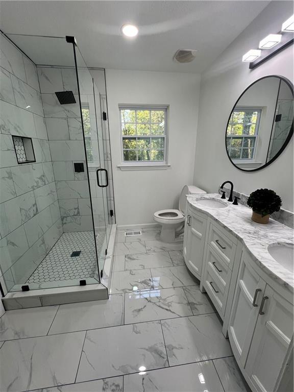 bathroom featuring a shower with door, vanity, and toilet