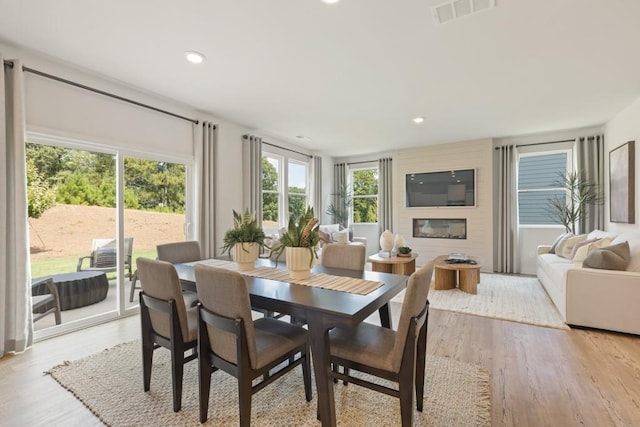 dining space with a large fireplace, light wood-type flooring, visible vents, and recessed lighting