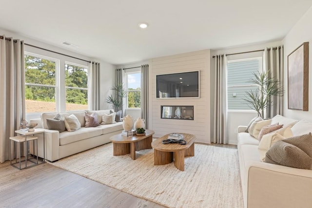 living room with light wood-style floors, recessed lighting, visible vents, and a fireplace